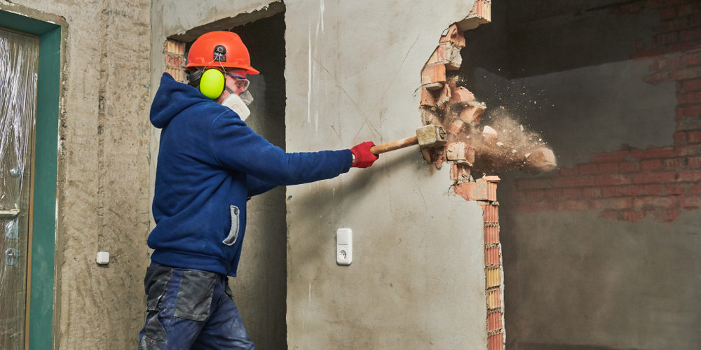 Demolition,Work,And,Rearrangement.,Worker,With,Sledgehammer,Destroying,Wall