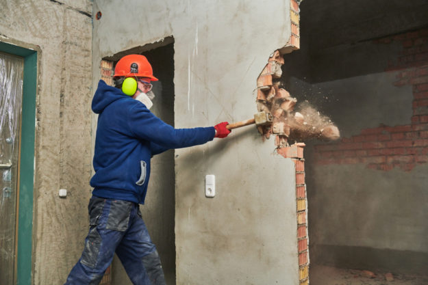 Demolition,Work,And,Rearrangement.,Worker,With,Sledgehammer,Destroying,Wall